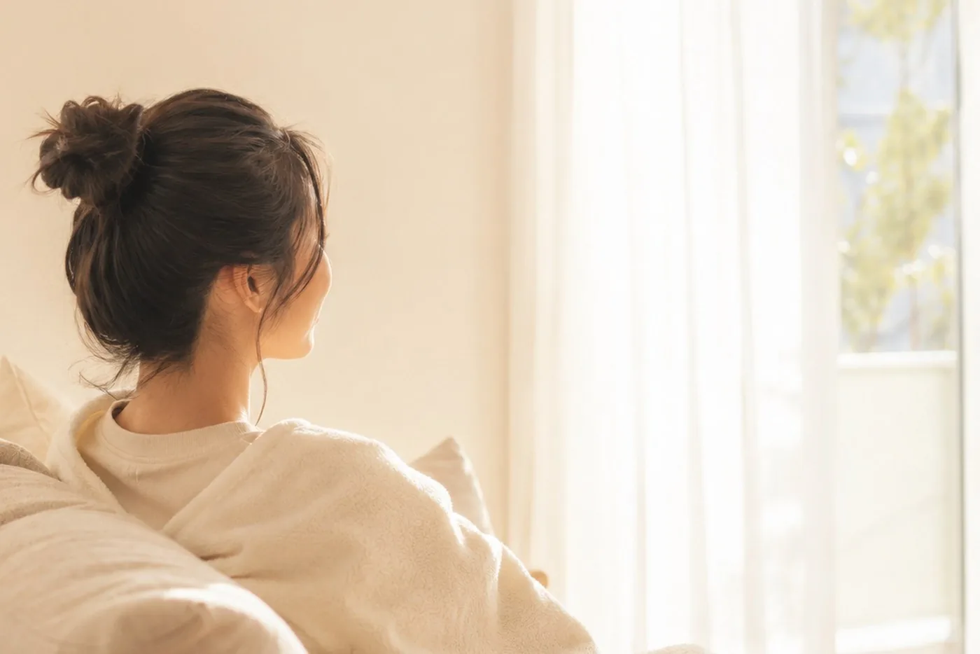ブランケットに包まれてソファでゆっくり休むお母さんの後ろ姿