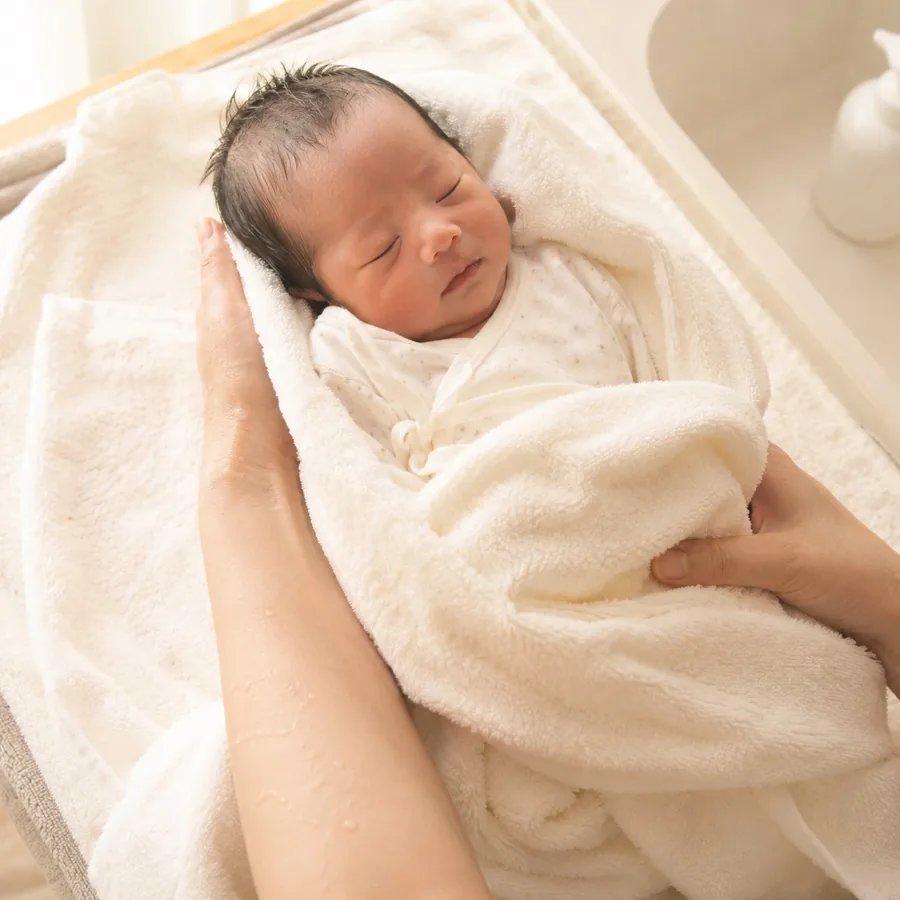 タオルに包まれた新生児を優しく支える助産師の手